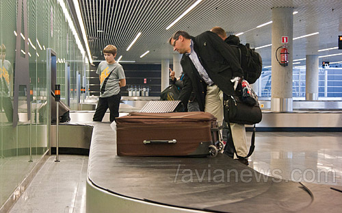 Пассажир забирает чемодан с багажной ленты в аэропорту